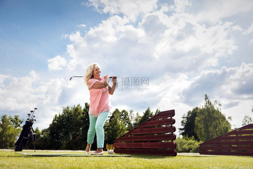 在高尔夫球场上打的活跃级女子夏季运动和爱好活跃的高级女子打尔夫图片