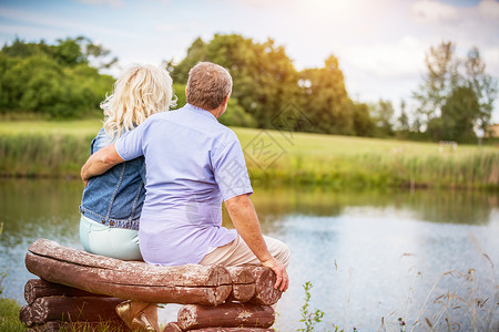 年老的婚姻坐在湖边长椅上退休活动幸福的成年夫妇老的婚姻坐在湖边长凳上图片