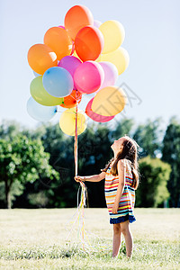 一堆草在公园里玩户外游戏小女孩在公园里拿着一堆多彩气球背景