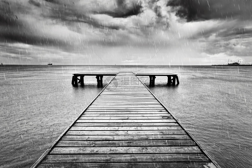 古老的木制码头在海上的从戏剧般的天空中降下黑暗的沉重云彩黑白旧码头在海上黑白雨图片