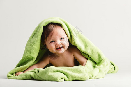 被绿色温暖的毯子覆盖着婴儿女孩躺在她的肚子上舒适和照顾图片