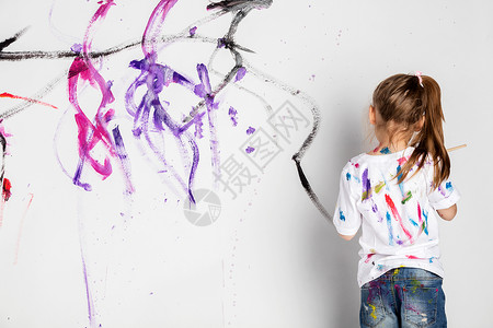 女孩画着彩色涂料的白墙图片