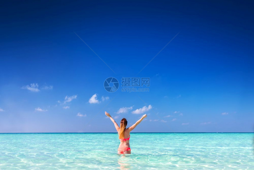 站在海洋中的美丽年轻女举起双手图片