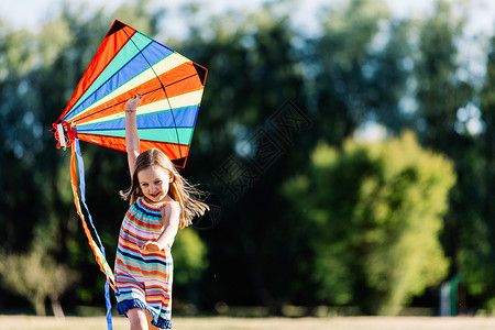 微笑的小女孩在公园里玩着多彩的风筝户外活动童年图片
