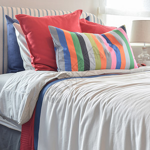 彩色灯板头巾上挂着彩色枕头和白床单上带色枕头和条的白床单背景