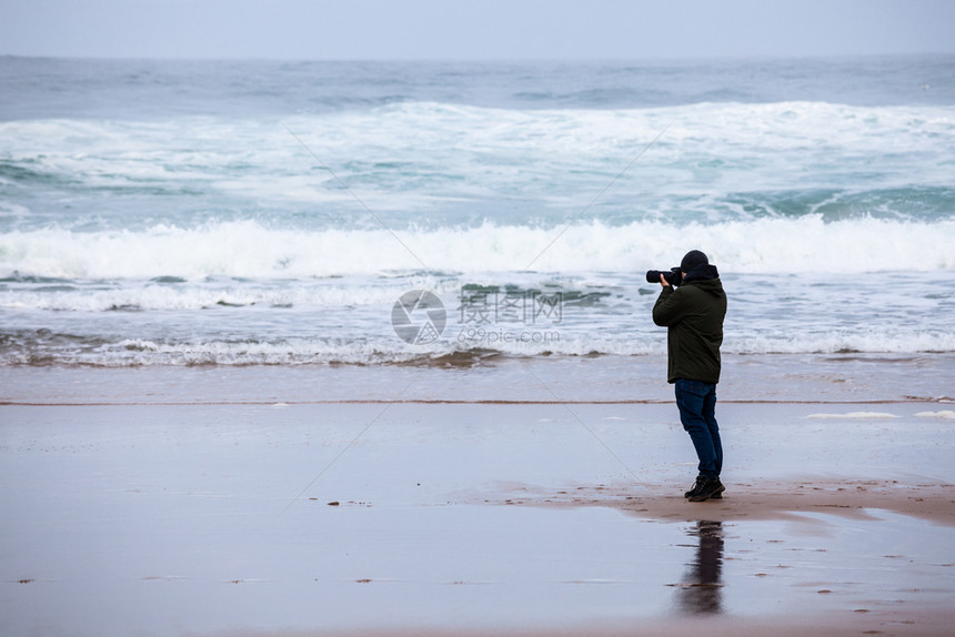 摄影记者在暴风海沙滩的休光片图片