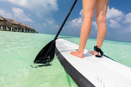 妇女在马尔代夫的海洋上站着划船桨高清图片