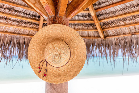 太阳帽挂在热带海滩的遮阳伞上印度洋马尔代夫图片