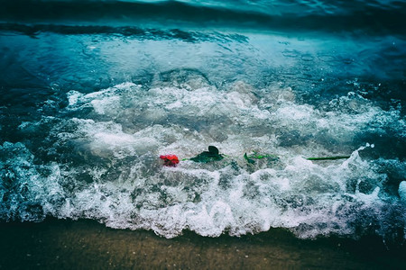 波浪洗去海滩上的红玫瑰浪漫爱情的概念浪漫但也可能象征失落忧郁回忆过去等传统波浪洗去海滩上的红玫瑰传统爱情背景图片