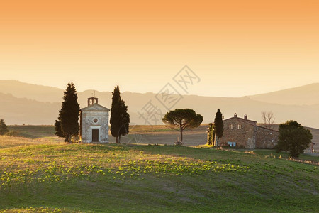 麦当娜日出时托斯卡纳风景与圣奎里科和奥尔西亚的圣奎里科德和尔斯小教堂日出时托斯卡纳风景与意大利马登纳和维塔的小教堂背景