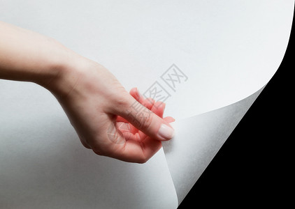 手拉着一个最底层的纸角揭开一些东西纸卷概念高清图片