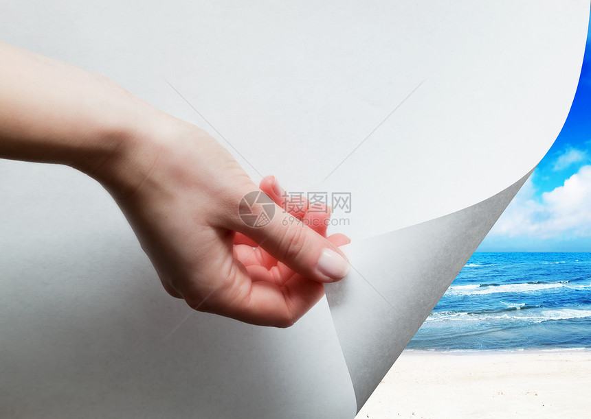 手拉着一个最底层的纸角发现揭示阳光灿烂的海滩图片