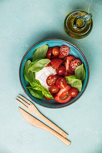 奶油沙拉莫扎雷奶酪西红柿和草药叶蓝色背景图片