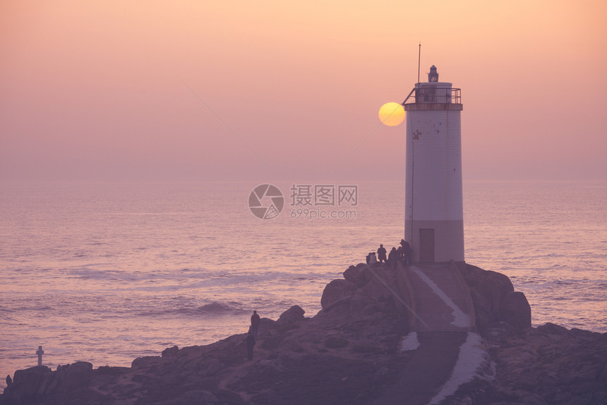 观看海洋日落的人们西班牙龙库多灯塔图片