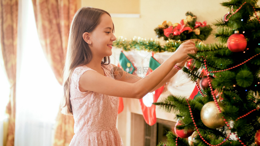美丽的笑少女在圣诞树上装饰着布勒的圣诞树美丽的笑少女肖像在圣诞树上装饰着布勒的圣诞树图片