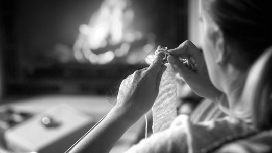 夜晚在壁炉边编织的年轻女黑白照片夜晚在壁炉边编织的年轻女黑白图像图片