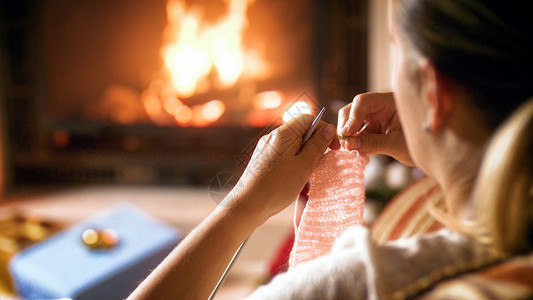 火针妇女用针织和羊毛坐在壁炉旁的近身照片妇女用针织和羊毛坐在壁炉旁的近身照片背景