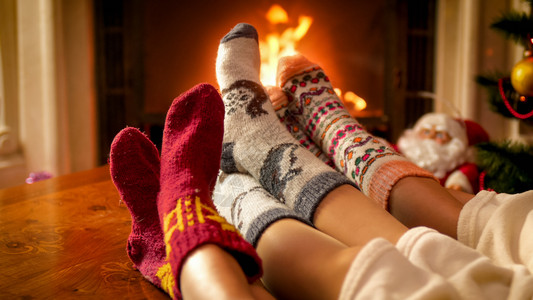 家庭穿着针织袜子在家中用燃烧的壁炉放松家庭穿着温暖的针织袜子图片