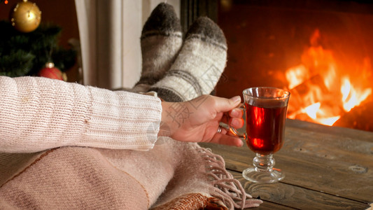 穿着羊绒袜子的妇女躺在壁炉边喝热茶图片