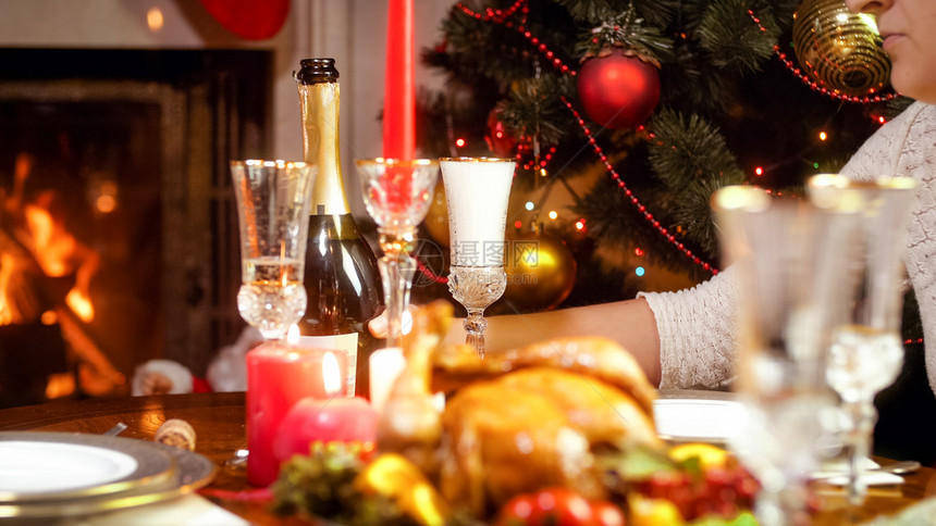 圣诞节家庭晚宴期间妇女把香槟杯放在餐桌上圣诞节家庭晚宴期间青年妇女把香槟杯放在餐桌上图片