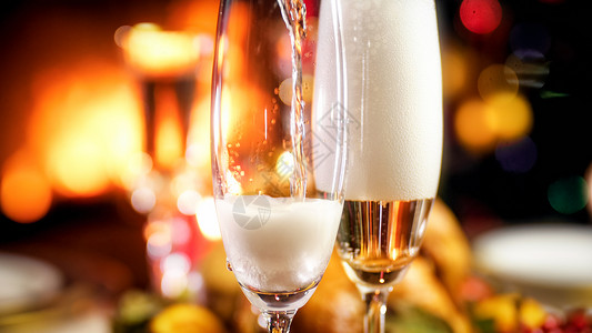 在壁炉的浪漫晚宴上香槟用玻璃杯在壁炉的浪漫晚宴上图片