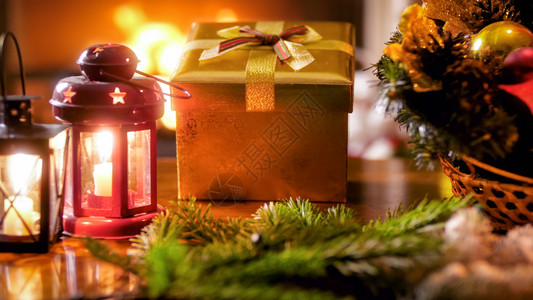 灯笼礼品盒和圣诞花圈对着燃烧的壁炉图片