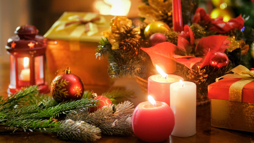 在圣诞节花圈和礼品盒上燃烧蜡烛的近镜头图片