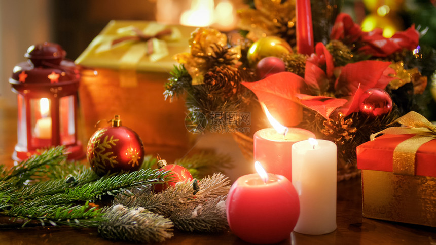 木制桌上燃烧蜡烛和圣诞装饰的美丽近镜头图片
