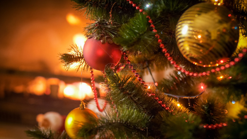 圣诞树上红色和金的面包圈与烧火壁炉圣诞树上红色和金的面包圈与烧火壁炉对比图片