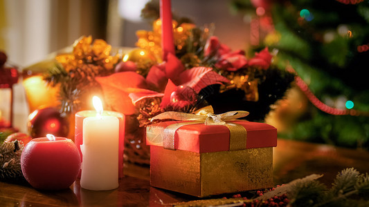 在圣诞树对面的木制桌子上对圣诞树的蜡烛和礼品贴合照片图片