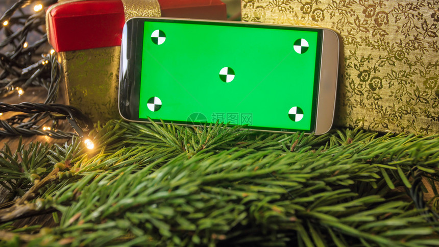 与圣诞装饰相比带空绿色屏幕的智能手机特亮照片文本或图像的位置与圣诞装饰相比带空绿色屏幕的智能手机特亮图像文本或的位置图片