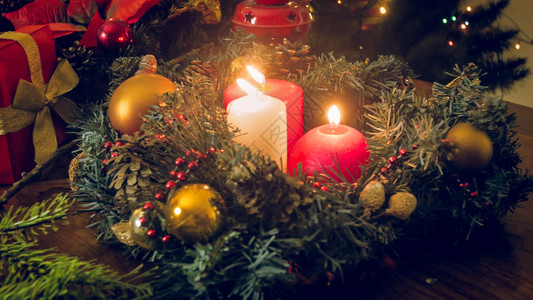 在装饰圣诞花圈中三支烧蜡烛的粉红色照片图片
