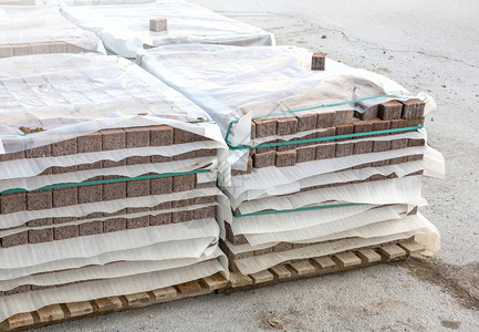 水泥或可腐灰白方形路面板或地墙堆在工厂仓库木托盘上的路面石块或图片