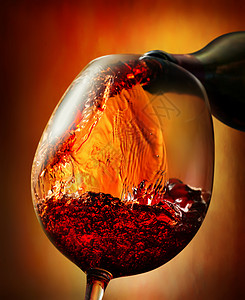 红酒倒入橙色背景的葡萄酒杯背景图片