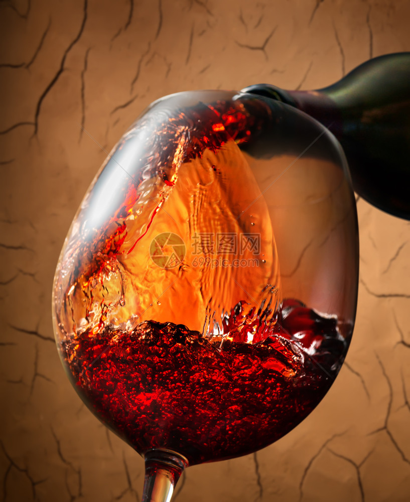红酒倒入粘土背景的葡萄酒杯中图片