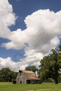 一个老古的谷仓坐在一片草地上蓝天下一片青草地上白云笼罩着图片