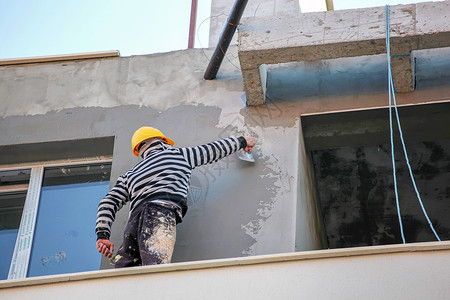 建筑房屋墙壁的石膏混凝土工人高清图片