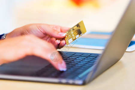 电子商务网上购物和互联付款概念年轻妇女在笔记本或上工作手持金信用卡图片