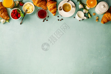 咖啡橙汁羊角面包果酱莓牛奶和鲜花蓝混凝土工作台为背景图片
