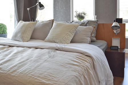时髦的卧室内设计床边有白条纹枕头和装饰桌灯图片