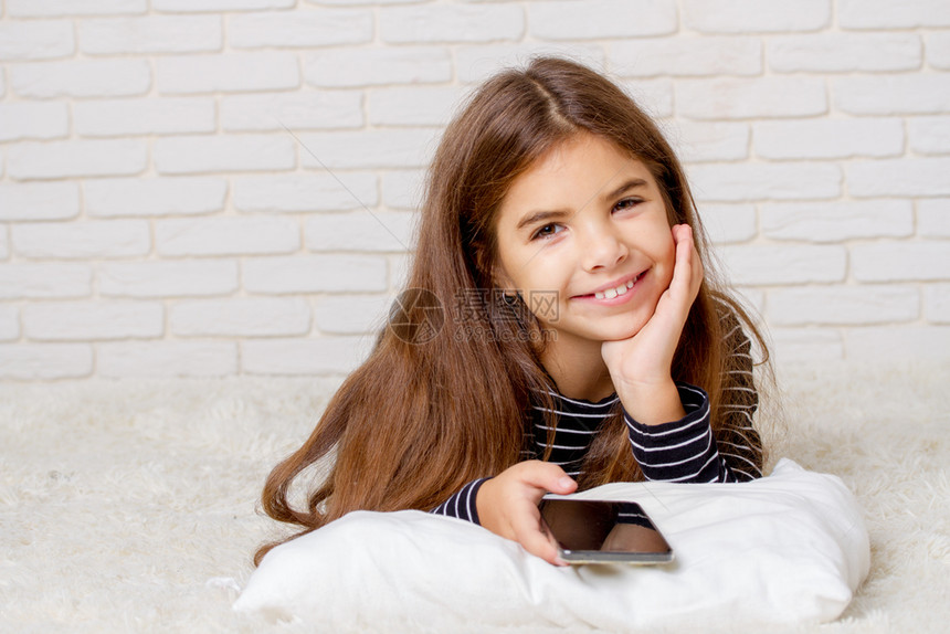女孩在床上躺玩智能手机游戏图片