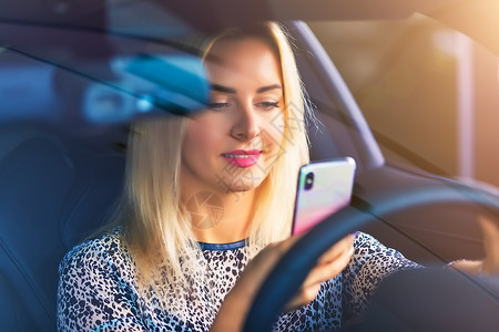 坐在轿车使用手机的女驾驶员图片