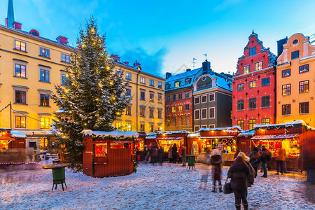 在瑞典斯德哥尔摩老城GamlaStan大广场Stortororget举行圣诞节日展会的美丽寒冬雪风景背景图片