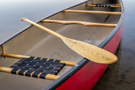 红色独木舟在平静的湖上用木板桨图片