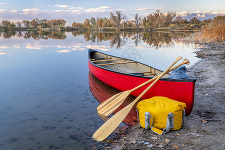 在科罗拉多落下风景的湖岸上有木桨和干袋的红色独木舟在科罗拉多落下风景背景