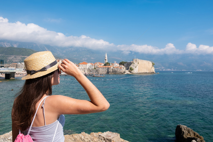 一位戴着帽子的年轻美女看着黑山的老城布德瓦夏季度假目的地图片
