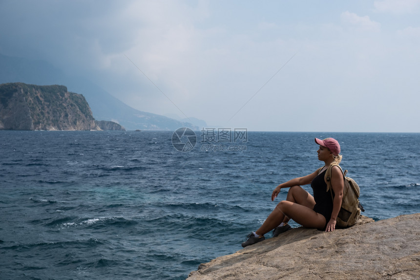 一个金发女孩坐在山顶看着海滩放松自然旅行图片