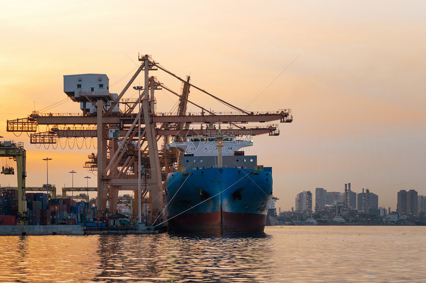 进出口企业的集装箱货船和城市的物流国际货日落时用起重机将货物运往港口图片