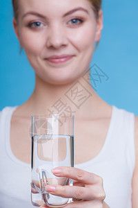 水力健康饮食用概念女人拿着一杯水工作室拍着蓝底背景图片