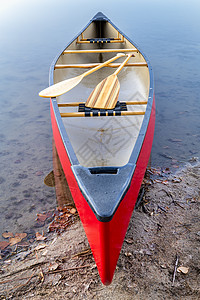在湖岸带木板的红色独舟图片